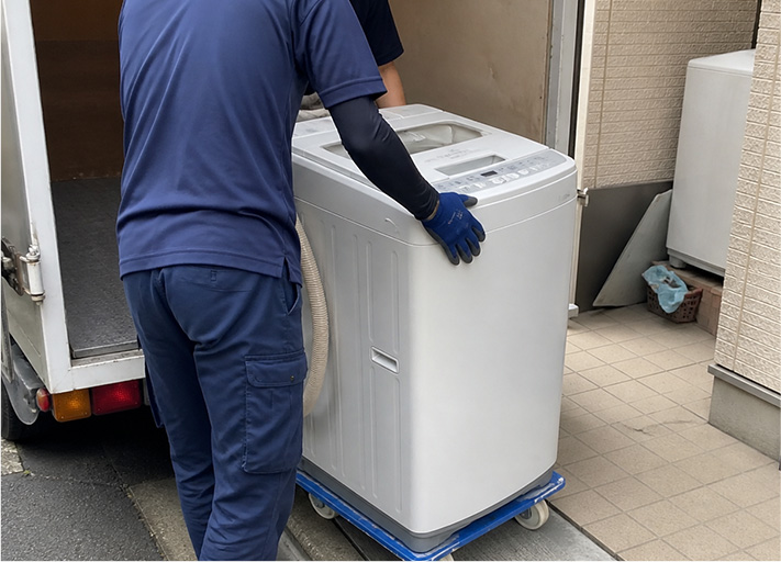 洗濯機を回収する作業員の画像